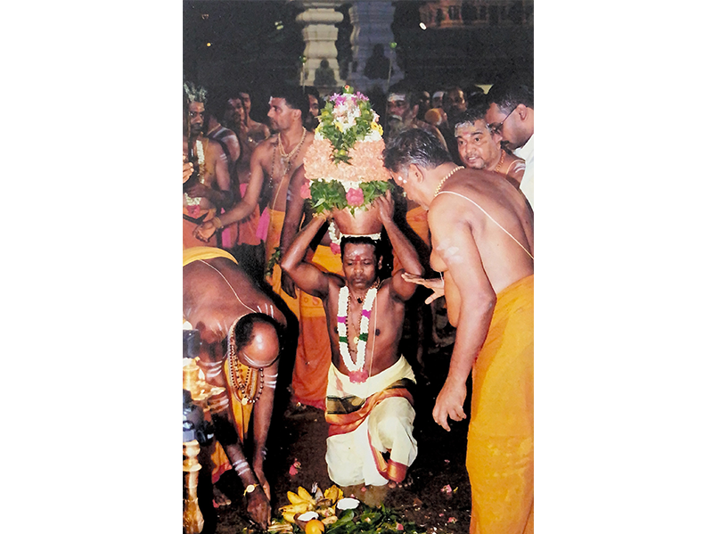 Chief pandaram K. Swaminathan placing the karagam on his head ahead of the foot procession to Sri Mariamman Temple, early 2000s. The karagam is a consecrated vessel embodying the mother goddess at Amman temples. Courtesy of Balakrishnan Veerasamy.
